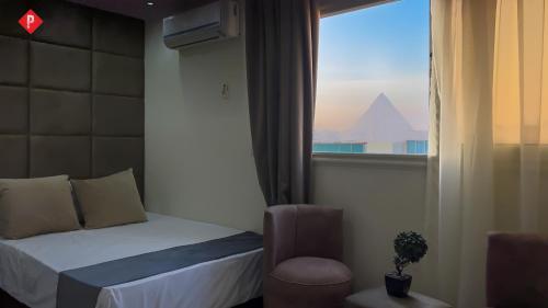 a bedroom with a bed and a window with a chair at Pyramids Residence view inn in Cairo