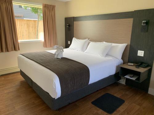 a bedroom with a large bed with a teddy bear on it at Cairns Motel in Summerside