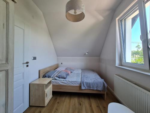 ein kleines Schlafzimmer mit einem Bett und einem Fenster in der Unterkunft MiLeśnik- domek całoroczny in Sztutowo