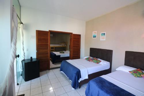 a hotel room with two beds and a mirror at Pousada Praia Mongaguá em Frente ao Mar com Piscina e Churrasqueira in Mongaguá