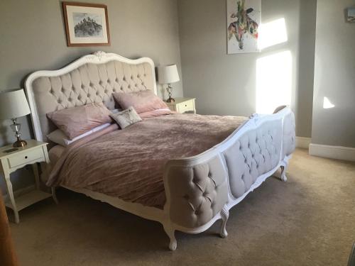 ein Schlafzimmer mit einem großen weißen Bett mit rosa Kissen in der Unterkunft Plas Bostock Farm in Wrexham