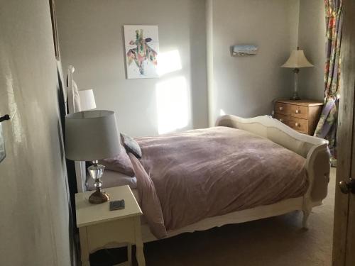 um quarto com uma cama e uma mesa com um candeeiro em Plas Bostock Farm em Wrexham