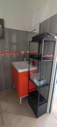 La salle de bains est pourvue d'un lavabo et d'une armoire rouge. dans l'établissement Chambre d'hôtes Chante Cigale, à La Ciotat