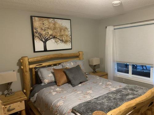 um quarto com uma cama com uma imagem de árvore na parede em Dragonfly Inn Loft & Walkout Suites em Sherwood Park