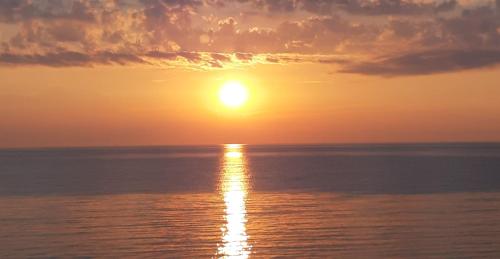 Sea View Apartments Poseidon في ليبتوكاريا: غروب الشمس على المحيط مع الشمس في السماء