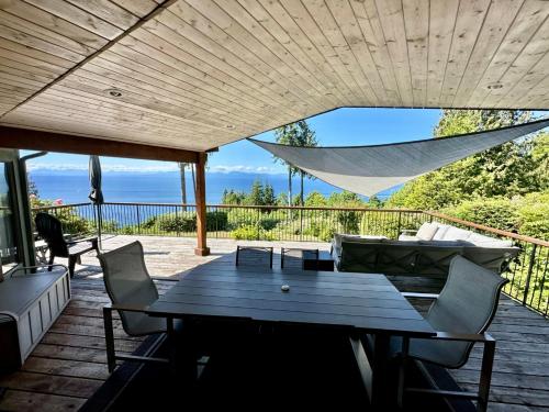 a patio with a table and chairs on a deck at Barooga: Stunning View Home in Halfmoon Bay, Canada in Halfmoon Bay