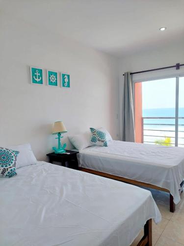 two beds in a bedroom with a view of the ocean at KaiBlue Hotel y Restaurante in La Libertad