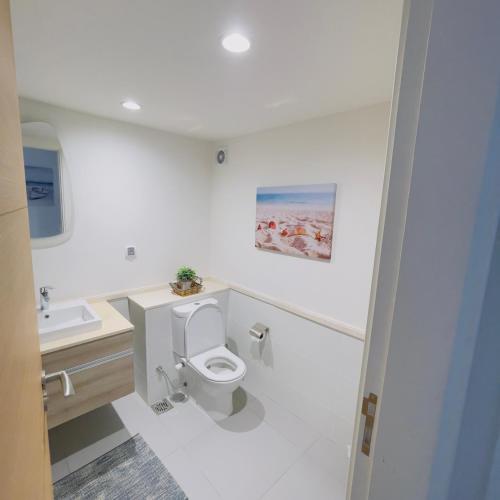 uma casa de banho branca com um WC e um lavatório em شالية بمراسي فرش فندقي السعر شامل الكروت em El Alamein