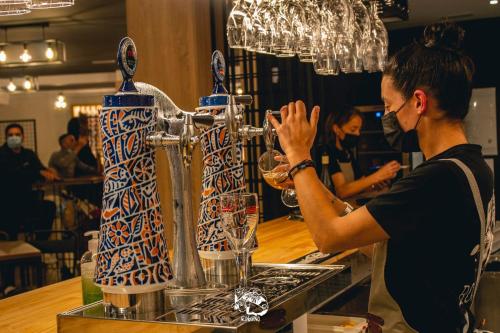 un homme debout devant un comptoir avec un mélangeur de boissons dans l'établissement Hotel Roquiño, à Caldas de Reis