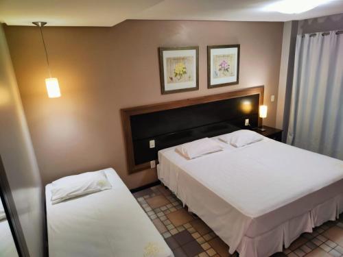 a hotel room with two beds and two tables at GoldMen Business Sorriso in Sorriso