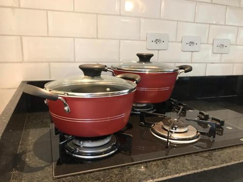2 casseroles assises au-dessus d'une cuisinière dans l'établissement Casa de Condomínio em Maresias - Pertinho da praia, à Maresias