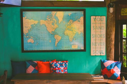 a map of the world hanging on a wall with pillows at Haleakala Hostel & Pousada in Praia do Rosa