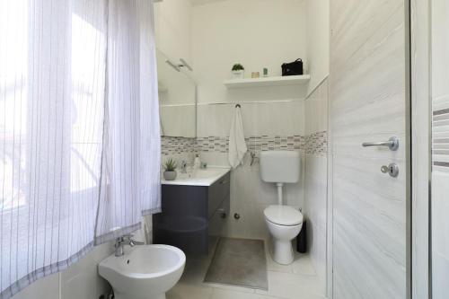 a white bathroom with a toilet and a sink at Lake House Valeriana in Pilzone