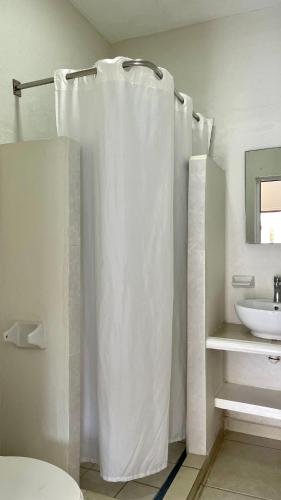 a bathroom with a white shower curtain and a sink at Bungalows Las Hamacas in San Patricio Melaque