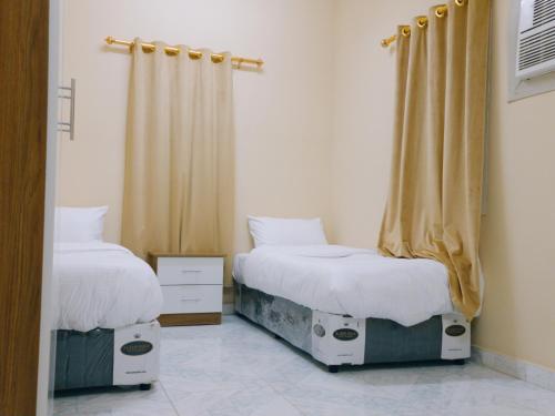 1 dormitorio con 2 camas y cortina en أجاويد Ajaweed en Salalah