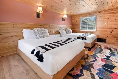 two beds in a room with wooden walls at Wolfjaw Lodge in Wilmington