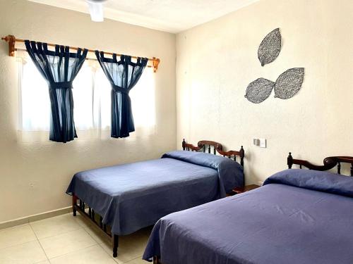 two beds in a room with butterflies on the wall at Bungalows Las Hamacas in San Patricio Melaque