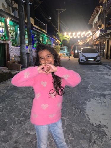 a young girl in a pink shirt standing on a street at Flet vista mar 1 in Arraial do Cabo