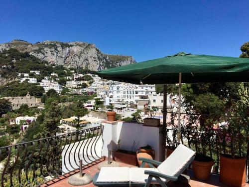 a balcony with a green umbrella and chairs at spettacolare suite Tragara Capri in Capri