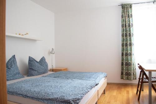Schlafzimmer mit einem Bett mit blauer Bettwäsche und einem Fenster in der Unterkunft Apartment Tereza in Prag