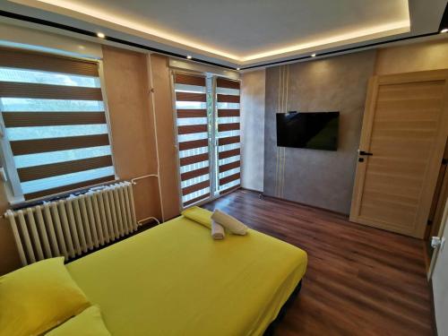 Pokój z żółtym łóżkiem i telewizorem w obiekcie Princ Lux Spa with free parking w Nowym Sadzie