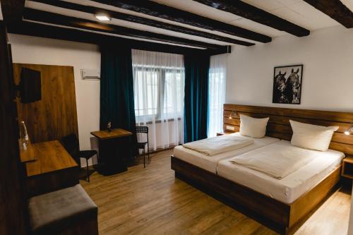 ein Schlafzimmer mit einem Bett und einem Schreibtisch in einem Zimmer in der Unterkunft Hotel Reiterhof-Altmühlsee in Gunzenhausen
