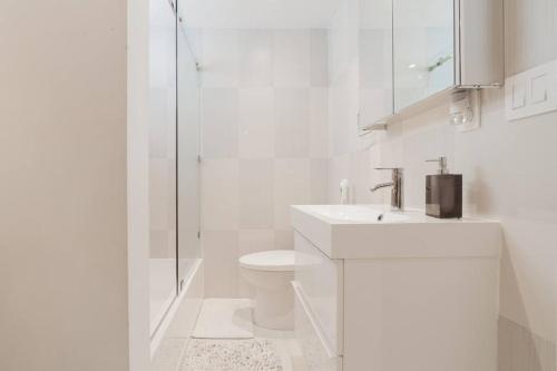 a white bathroom with a toilet and a sink at BEACH VIBES in Miami Beach