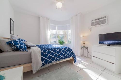 a white bedroom with a bed and a tv at BEACH VIBES in Miami Beach