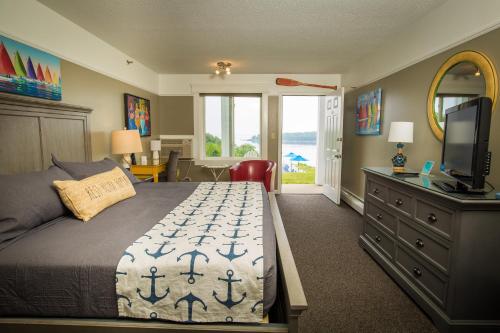 1 dormitorio con 1 cama y vestidor con TV en Strawberry Hill Seaside Inn, en Rockport