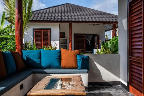 a patio with a blue couch and a table at Baobab Bungalows in Jambiani