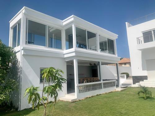 a white house with large windows and a yard at Appartement Luxueux En Résidence vu sur mer à 50 mètres de la plage in Sali Tapé