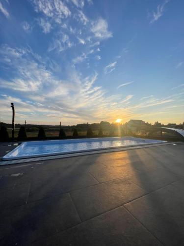 a swimming pool with the sunset in the background at Loox Ostrovo- Boutique House-noclegi nad morzem in Ostrowo