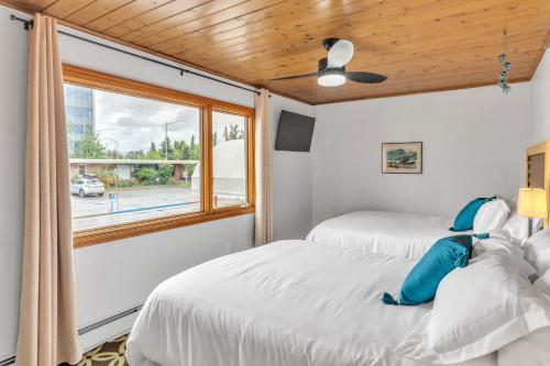 two beds in a room with a window at Highliner Hotel - Deluxe Double Queen with Mountain View in Anchorage