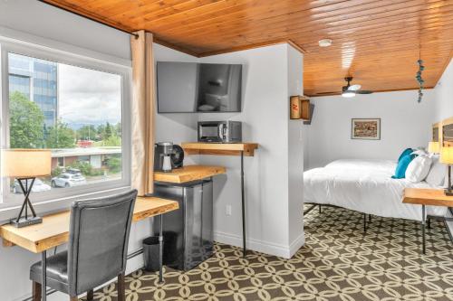 a room with a bed and desk and a window at Highliner Hotel - Deluxe Double Queen with Mountain View in Anchorage