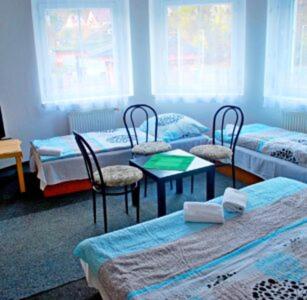 a room with three beds and a table and chairs at Penzion u Jakuba in Svoboda nad Úpou