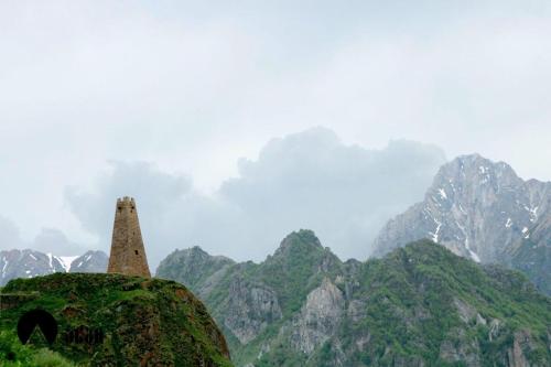 a stone tower in front of a mountain range at Cottage Shina in Kazbegi
