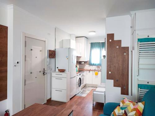 Una cocina con gabinetes blancos y un refrigerador blanco. en Bright and quiet studio in Málaga, en Málaga