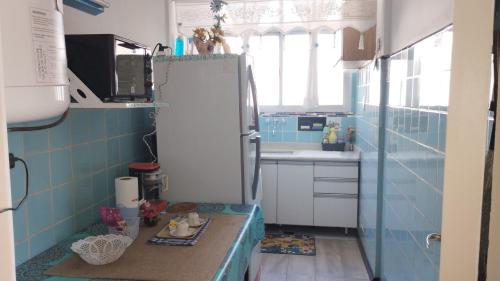 Una pequeña cocina con azulejos azules y una nevera blanca. en La perla y el mar en Mar del Plata