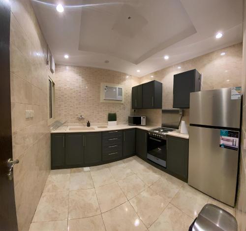 cocina con armarios negros y nevera de acero inoxidable en 2 Bedrooms Apartment in Makkah, en La Meca