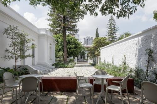 a patio with tables and chairs and a wall at Casa Bosque Eduviges in Guadalajara