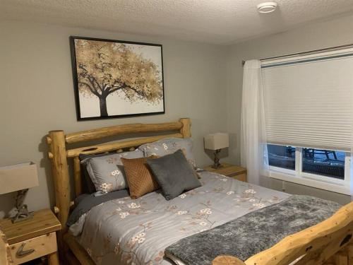 a bedroom with a bed with a tree picture on the wall at Dragonfly Inn Walkout Suites in Sherwood Park