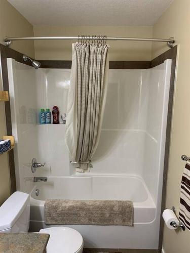 a bathroom with a white tub and a toilet at Dragonfly Inn Walkout Suites in Sherwood Park