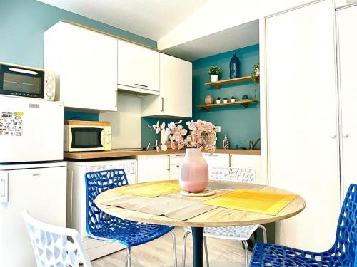 uma cozinha com uma mesa com cadeiras e um vaso sobre ela em Caporizon-La Moulinette-5min Gare et Port em La Rochelle