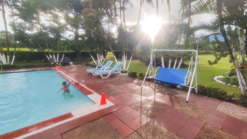 a boy in a swimming pool with a swing at Finca Turistica Rural El Descanso, privada Restrepo, Meta - Colombia in Restrepo