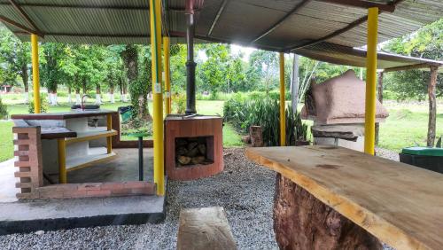 an outdoor grill with a wooden table and a wood stove at Finca Turistica Rural El Descanso, privada Restrepo, Meta - Colombia in Restrepo