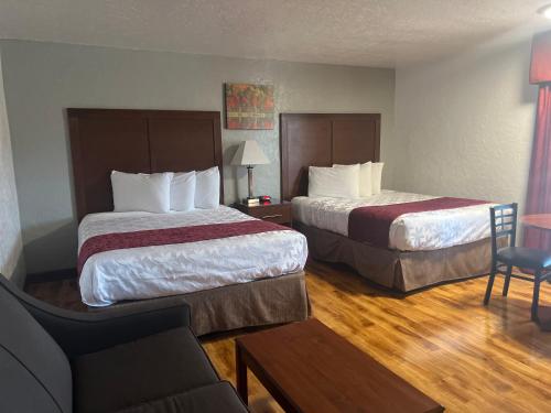 a hotel room with two beds and a couch at Red Carpet Inn Medford in Medford
