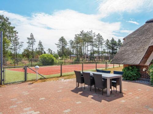 a patio with a table and chairs and a tennis court at 14 person holiday home in R m in Kongsmark