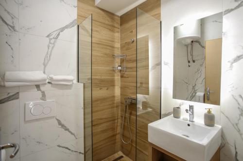 a white bathroom with a sink and a shower at Hotel Emen in Mostar