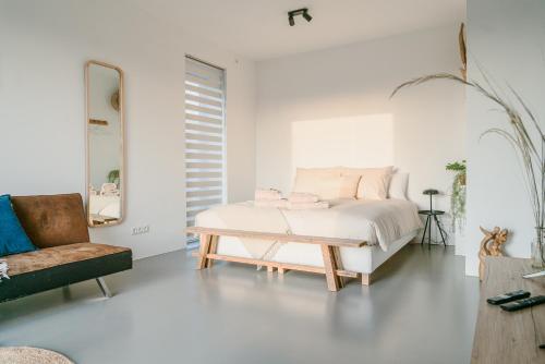 een witte slaapkamer met een bed en een stoel bij BNBNRD 2-Room Boutique Apartment Amsterdam Cultural District in Amsterdam