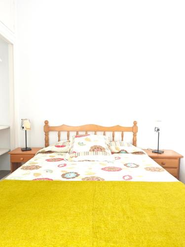 een slaapkamer met een groot bed en een gele deken bij Cozy Apartment in front of the Natural Pools in El Pris